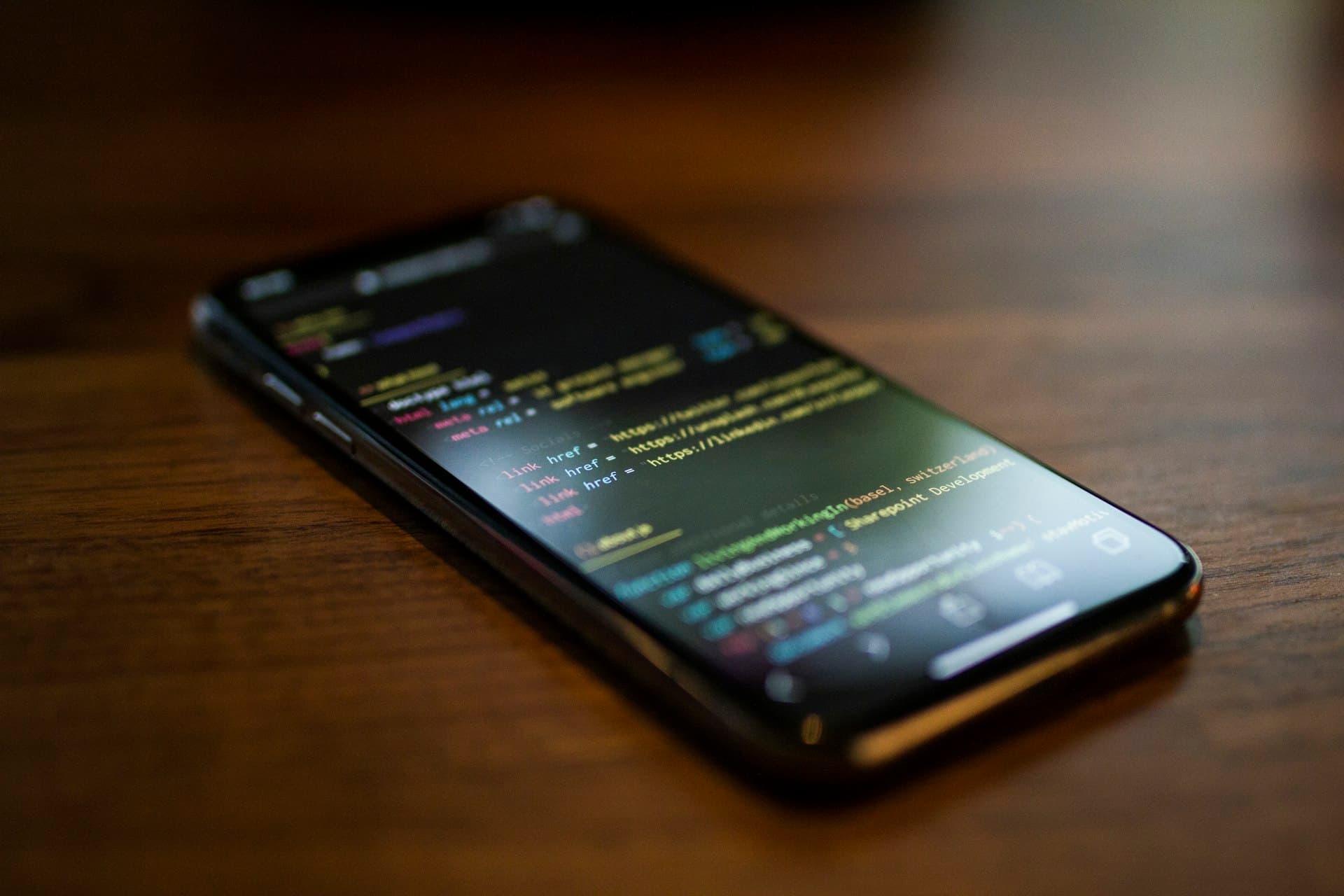 Smartphone showing a code editor on a desk